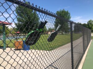 chainlink fence holding pickleball paddles